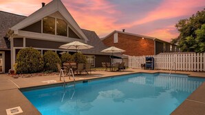 Una piscina con zona de terraza, espacio de estar cubierto y patio cercado.