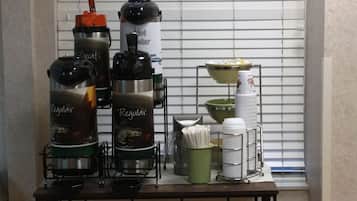 A kitchenette with coffee makers, a kettle, and a coffee dispenser on a table.