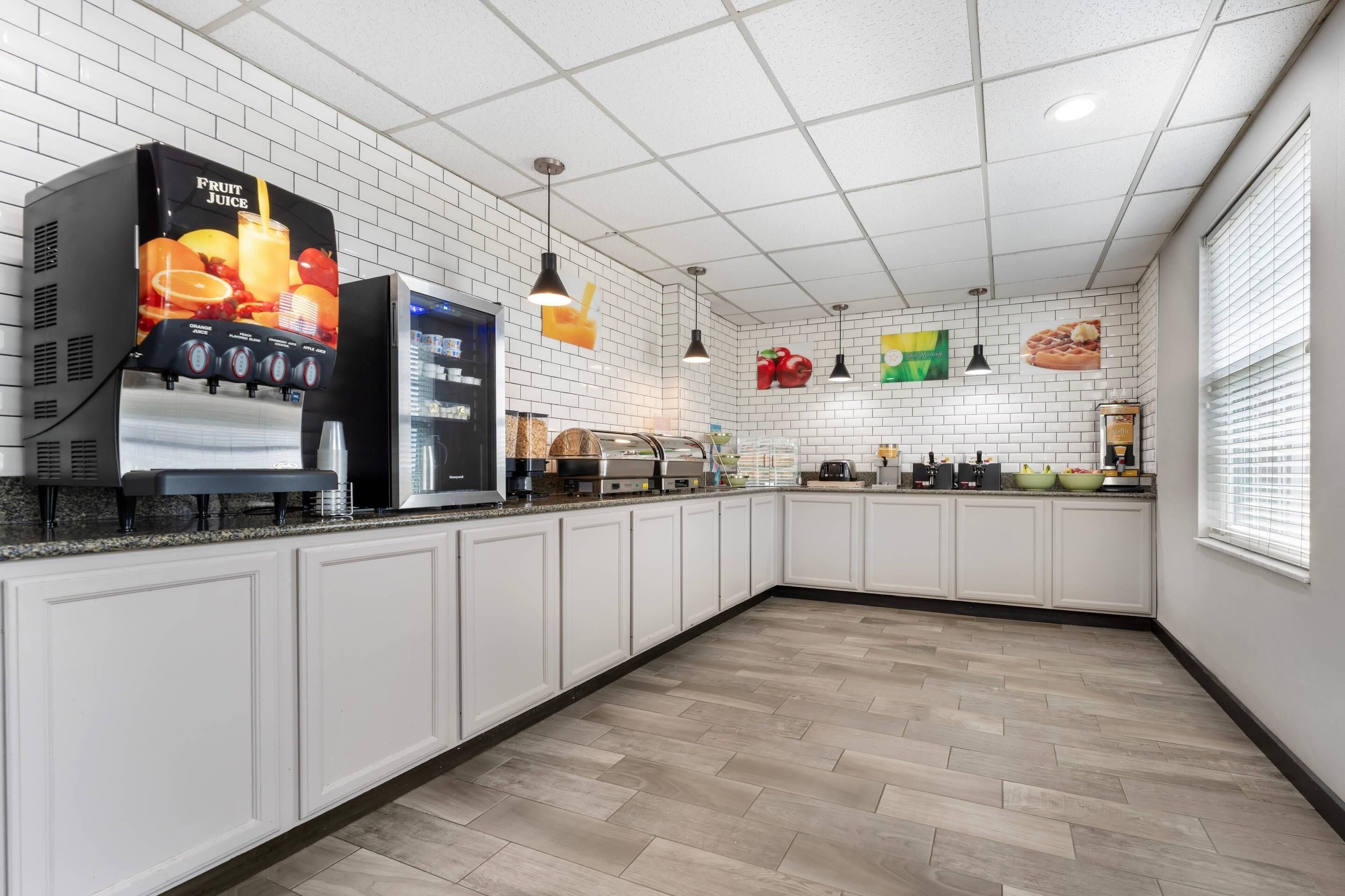 Una cucina moderna con mobili bianchi, un erogatore di succo di frutta e una macchina per il caffè.