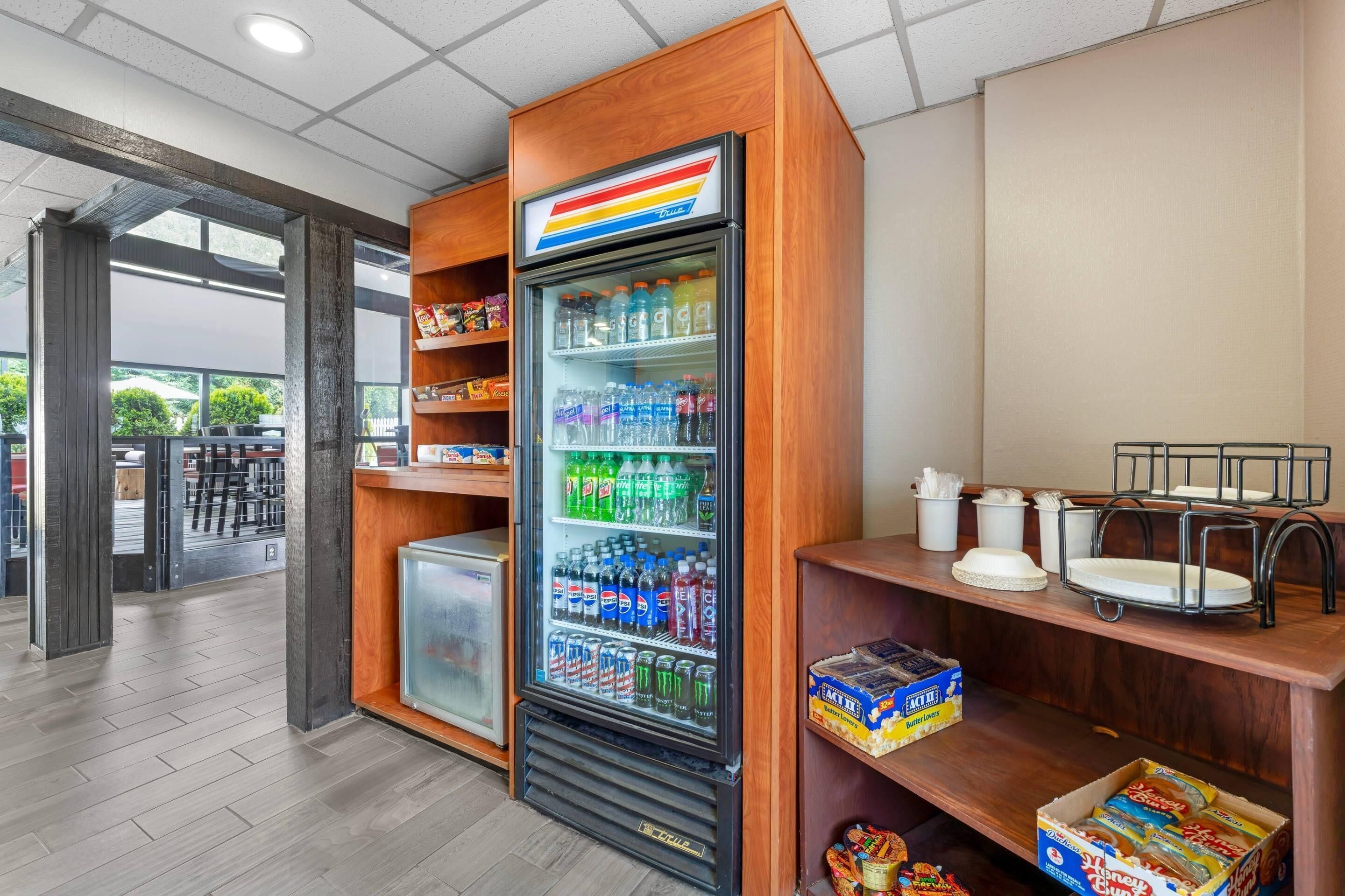 Máquina expendedora con aperitivos y bebidas, un refrigerador y una encimera con asientos.