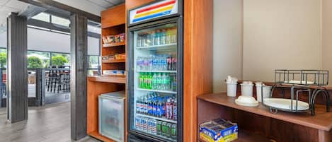 A vending machine with snacks and beverages, a refrigerator, and a counter with seating.