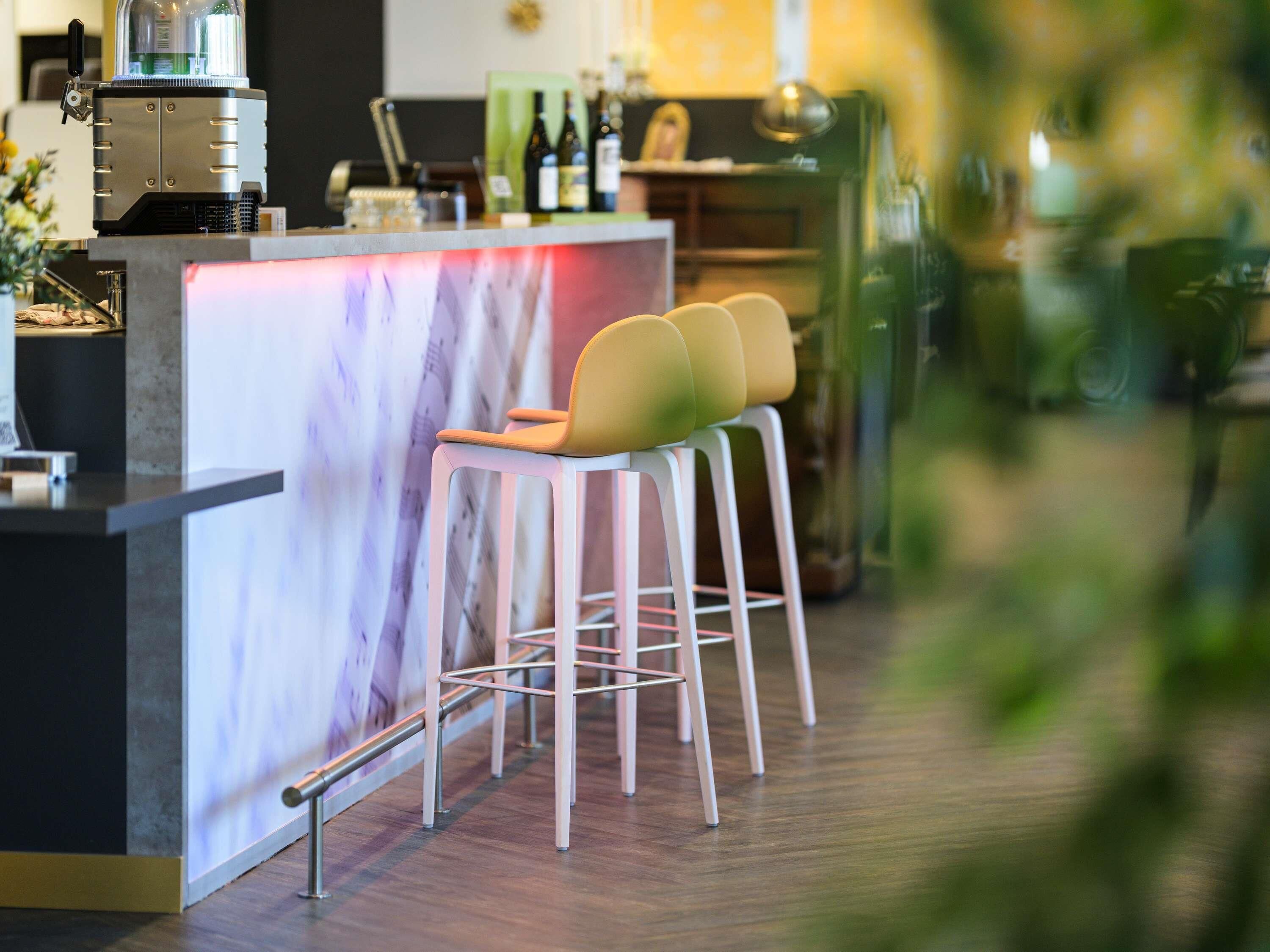 A bar area with stools, a counter, and a coffee machine.