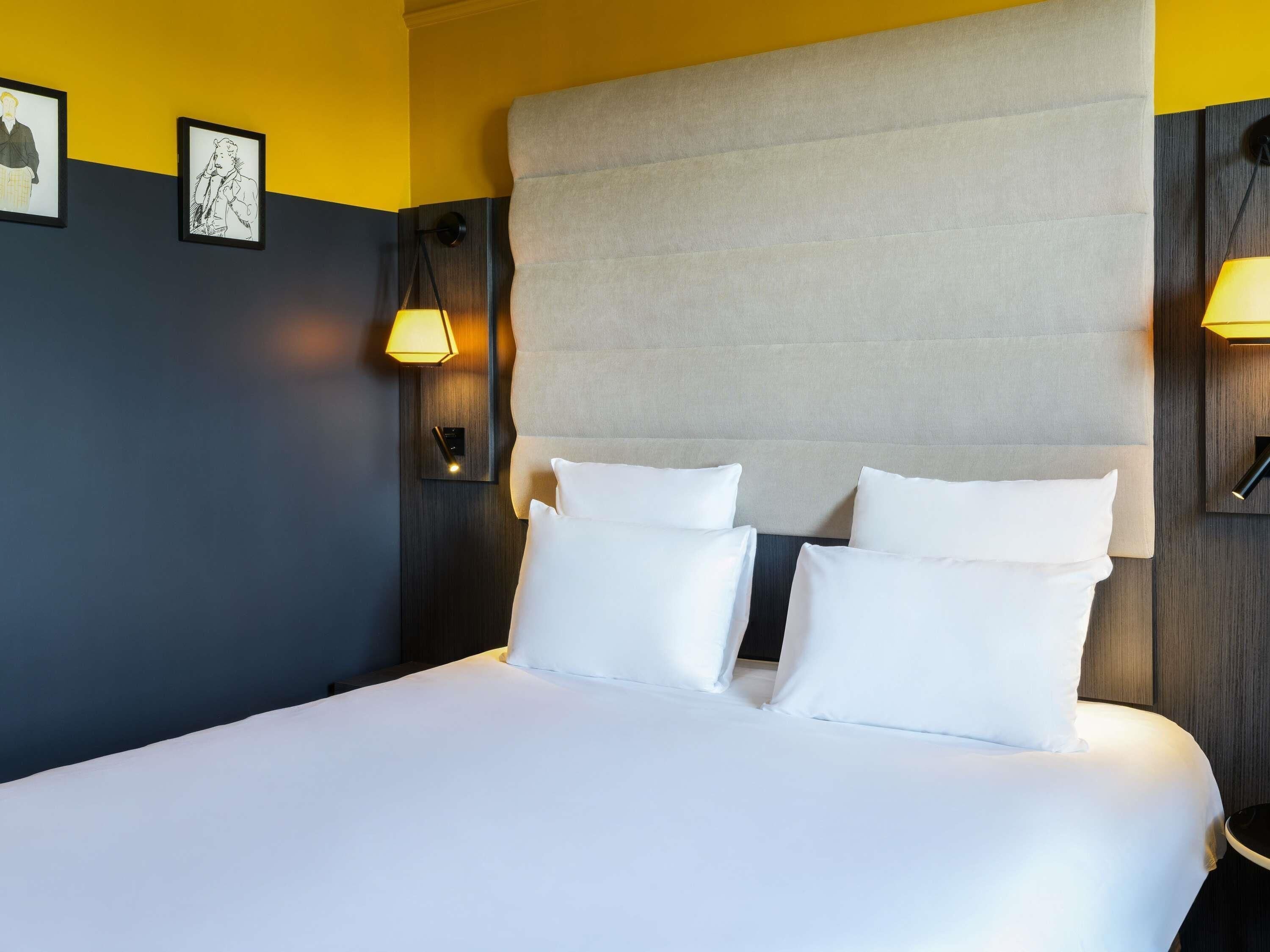 A hotel room with a large bed, two bedside lamps, and a headboard.