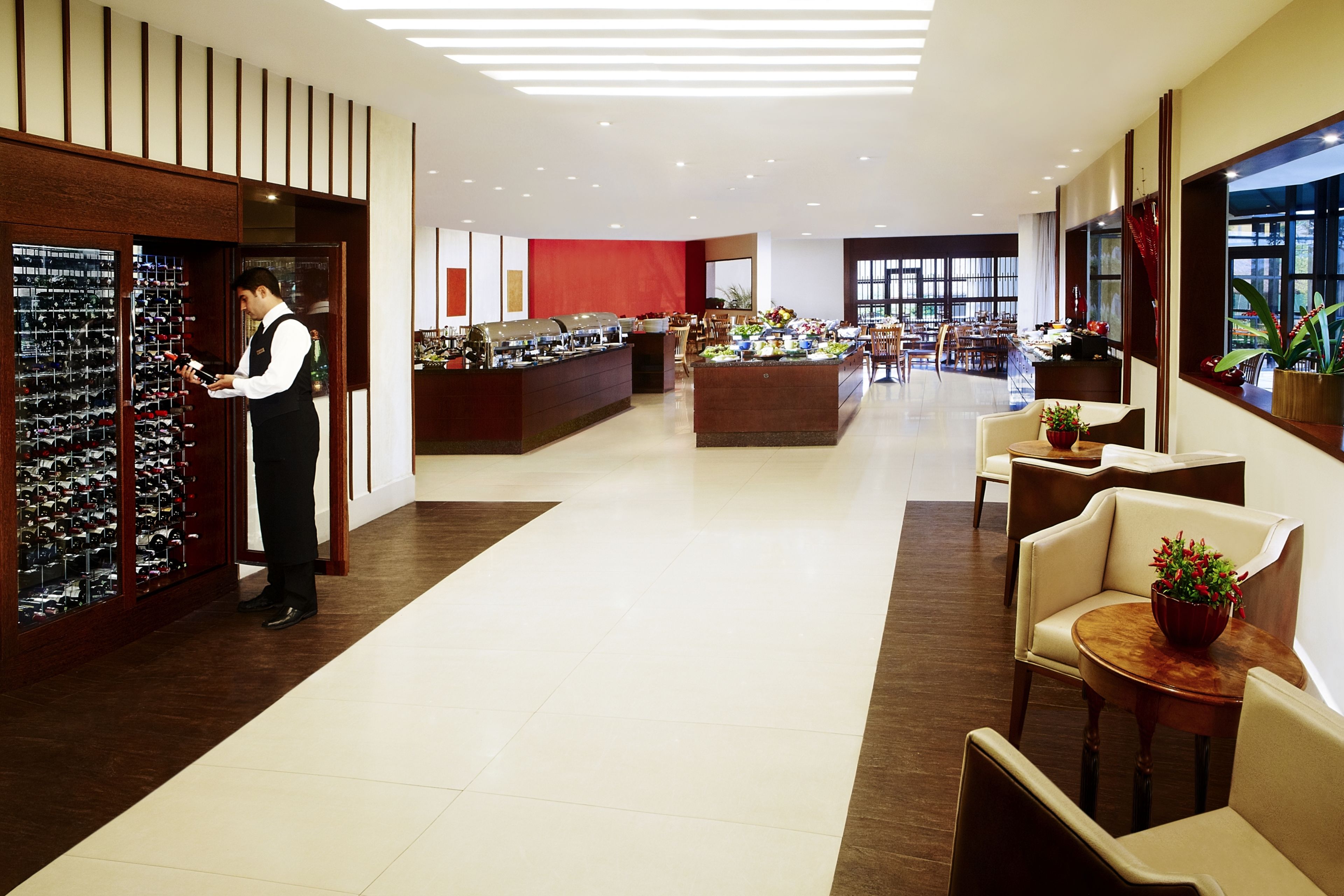 A hotel lobby with a wine display, seating area, and a reception desk.