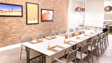 Uma sala de conferências com uma mesa comprida, cadeiras e quadros pendurados na parede.