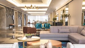A modern lobby with a grey sofa, teal chairs, and a coffee table with vases.