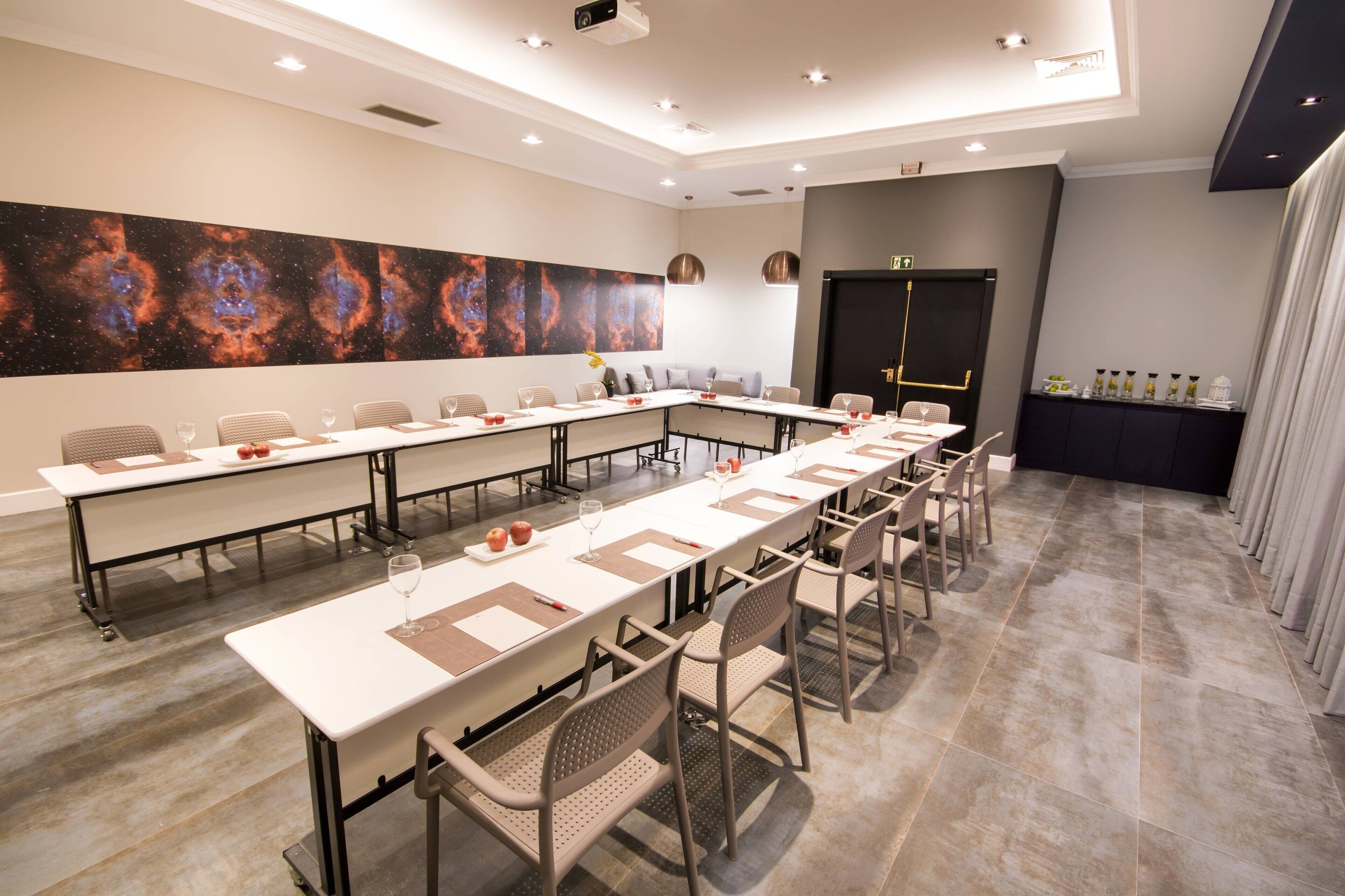 A conference room with a long table, chairs, and a large abstract painting on the wall.
