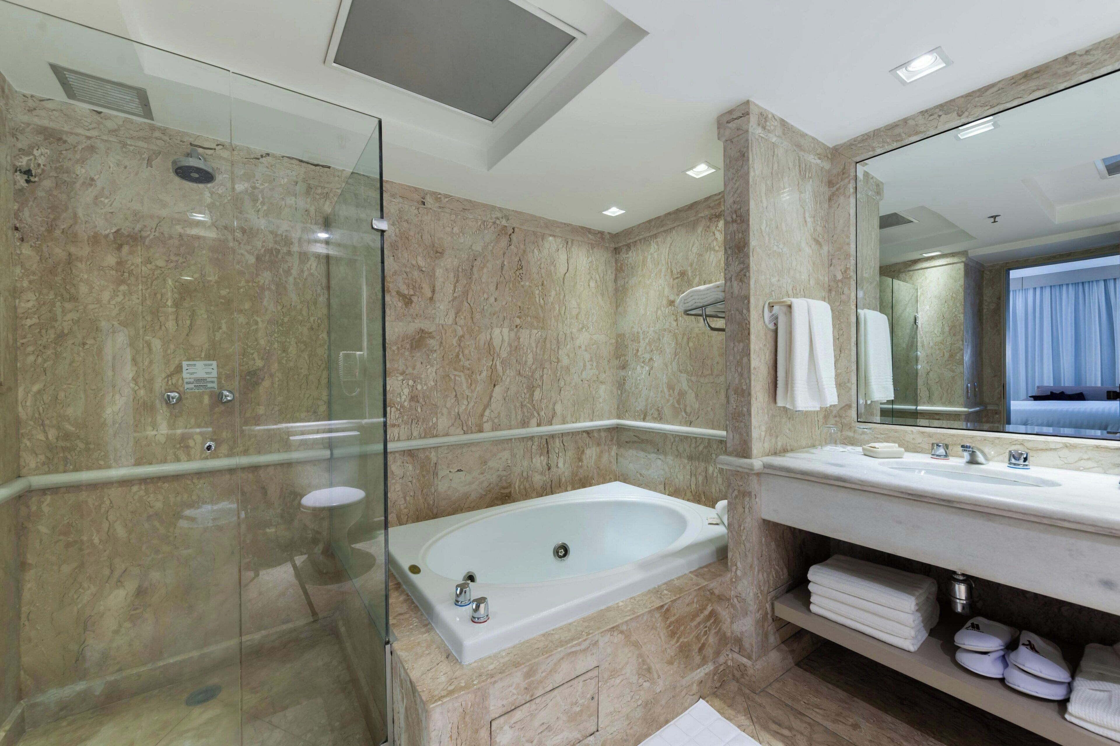 A modern bathroom with a glass-enclosed shower, a freestanding bathtub, and a vanity with a mirror.