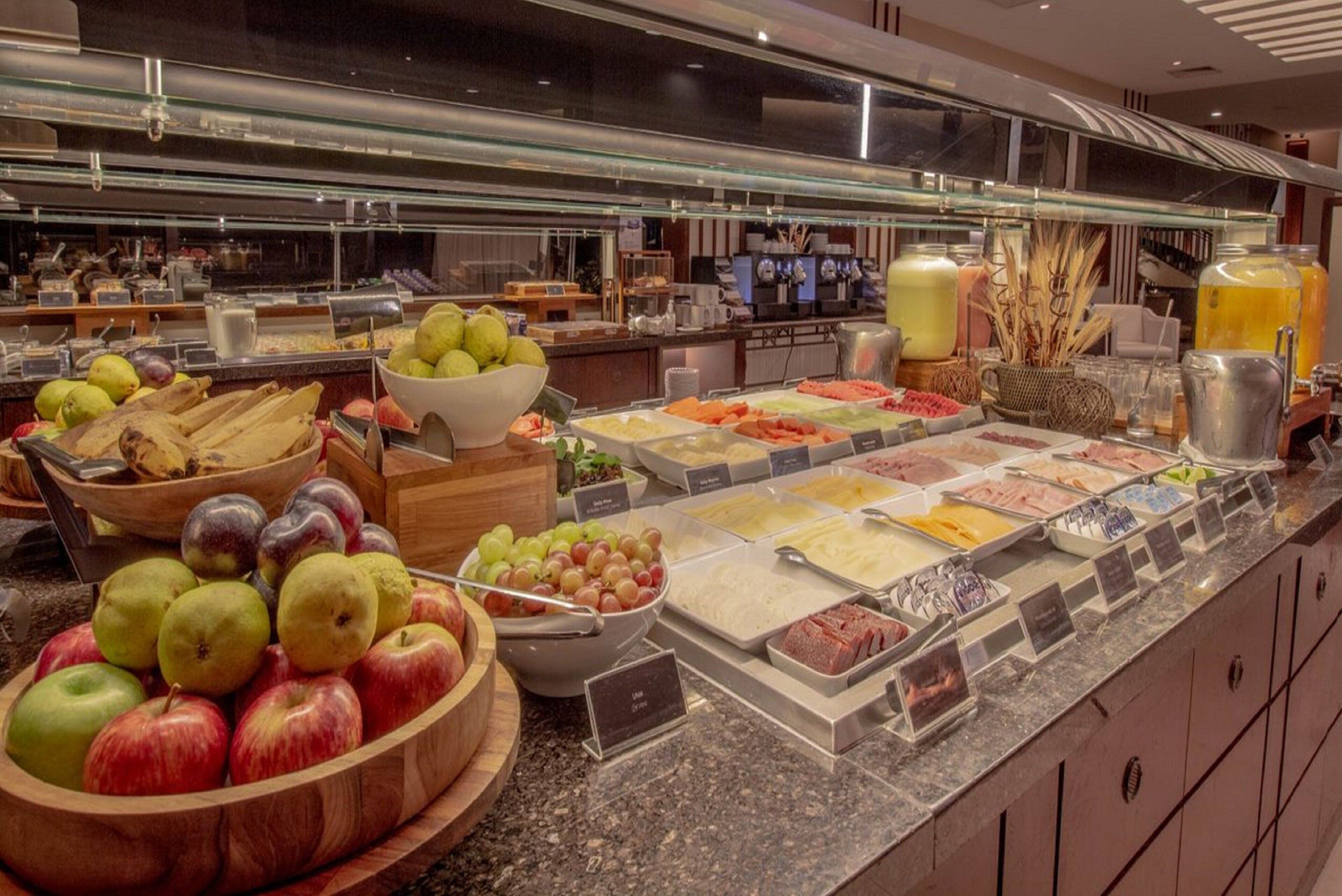 Buffet com diversos alimentos e uma tigela de maçãs.