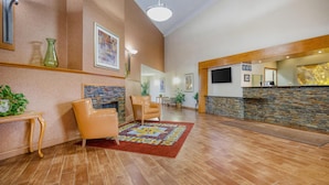 A lobby with a reception desk, leather chairs, a patterned rug, and a stone accent wall. - Best Western Davison Inn (Davison)