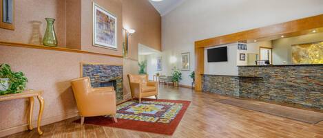 A lobby with a reception desk, leather chairs, a patterned rug, and a stone accent wall.