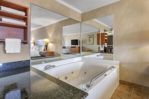 A modern bathroom with a large bathtub, a mirror, and a vanity with a countertop.