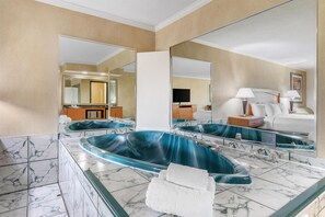 Un baño con una bañera grande, un espejo y piso de mármol.