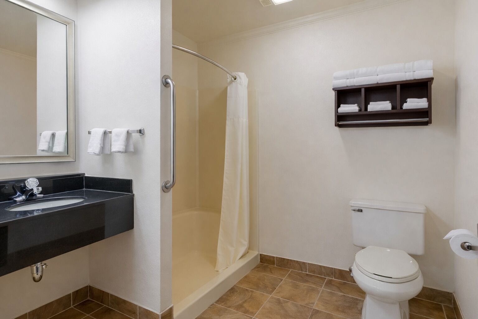 Une salle de bain avec une douche, des toilettes et une étagère avec des serviettes.