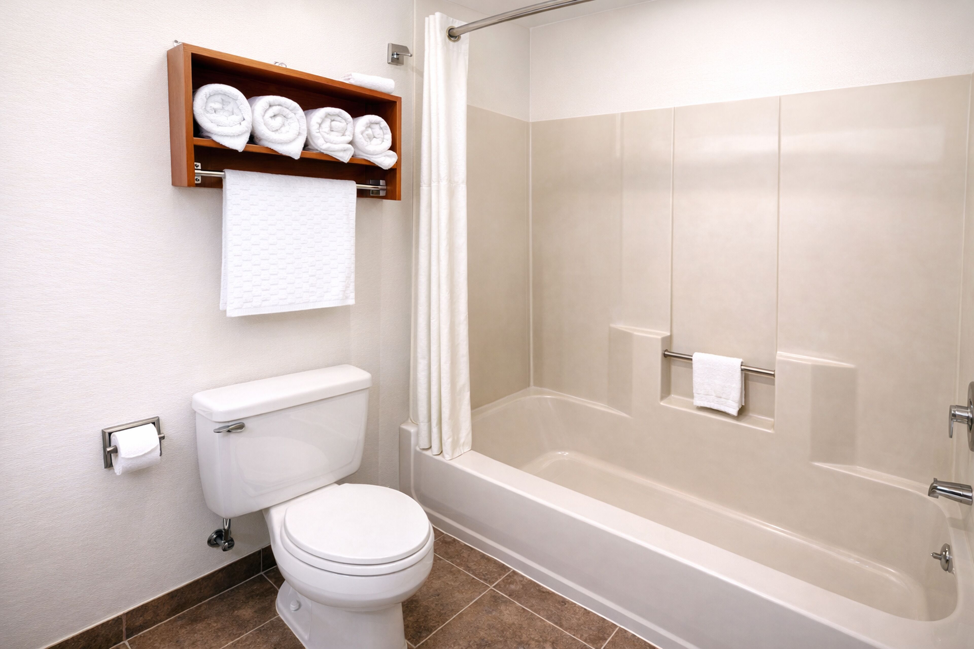 Un baño con inodoro, ducha con mampara de vidrio y toallero con toallas dobladas.