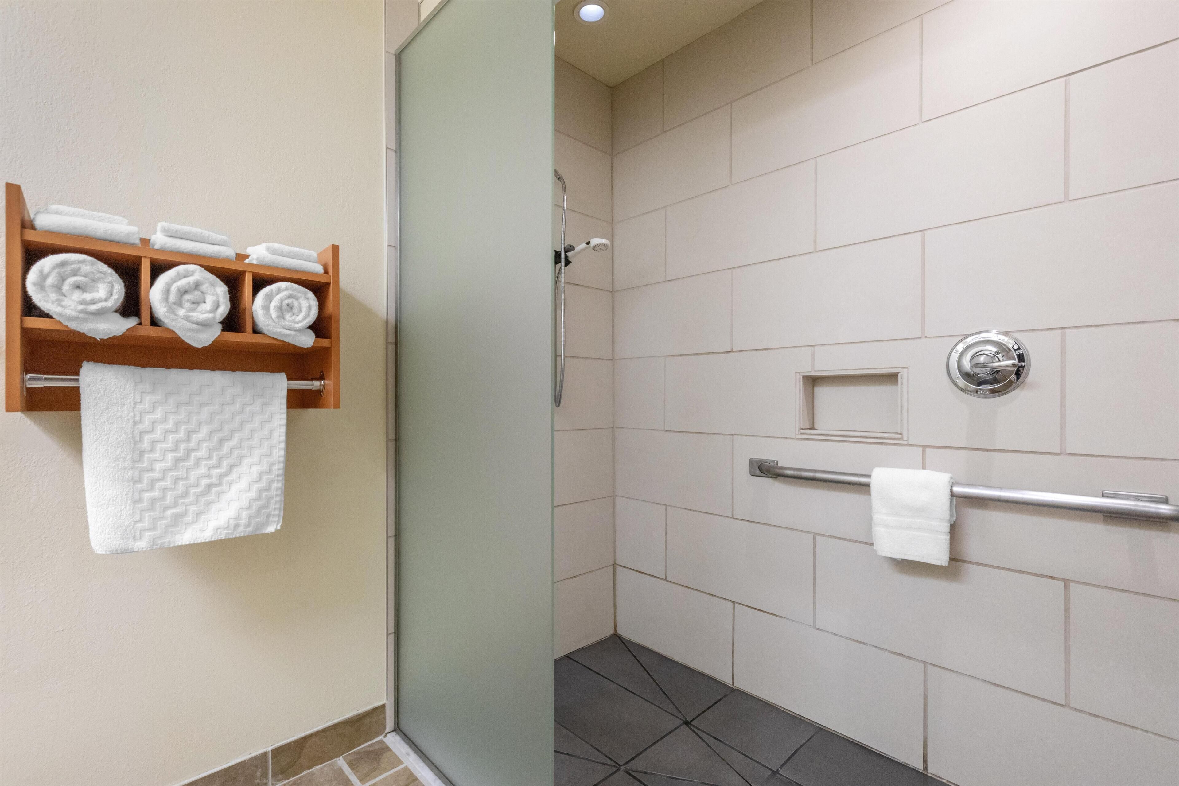 Un bagno con doccia, un portasciugamani con asciugamani piegati e una porta doccia in vetro.