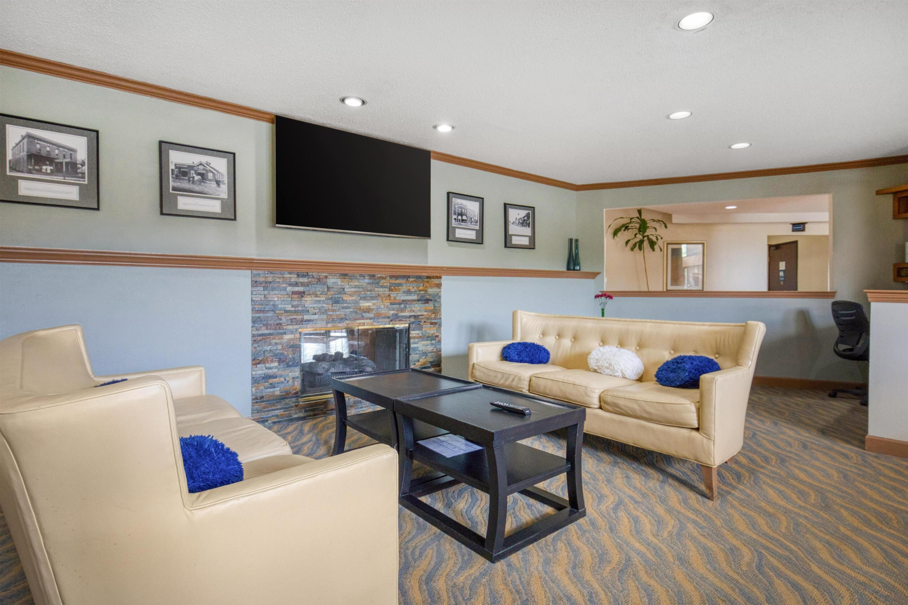 A lobby with a fireplace, a sofa, a coffee table, and framed pictures on the wall.