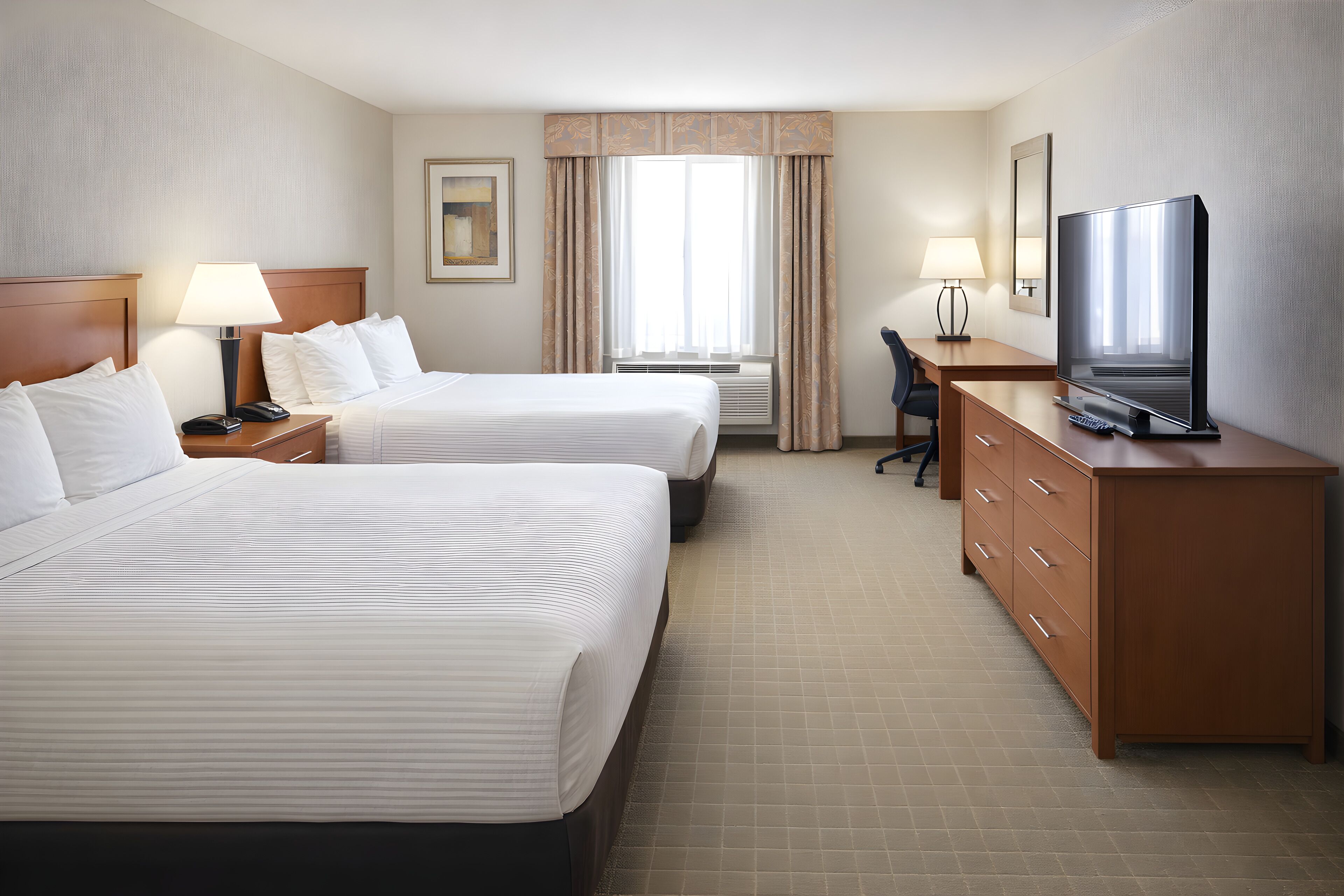 A hotel room with two beds, a desk, a television, and a window with curtains.