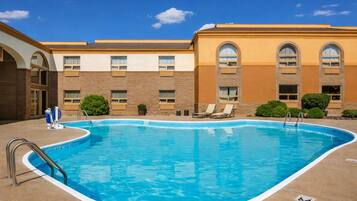 A swimming pool with a 'NO DIVING' sign, lounge chairs, and a building with arched windows.