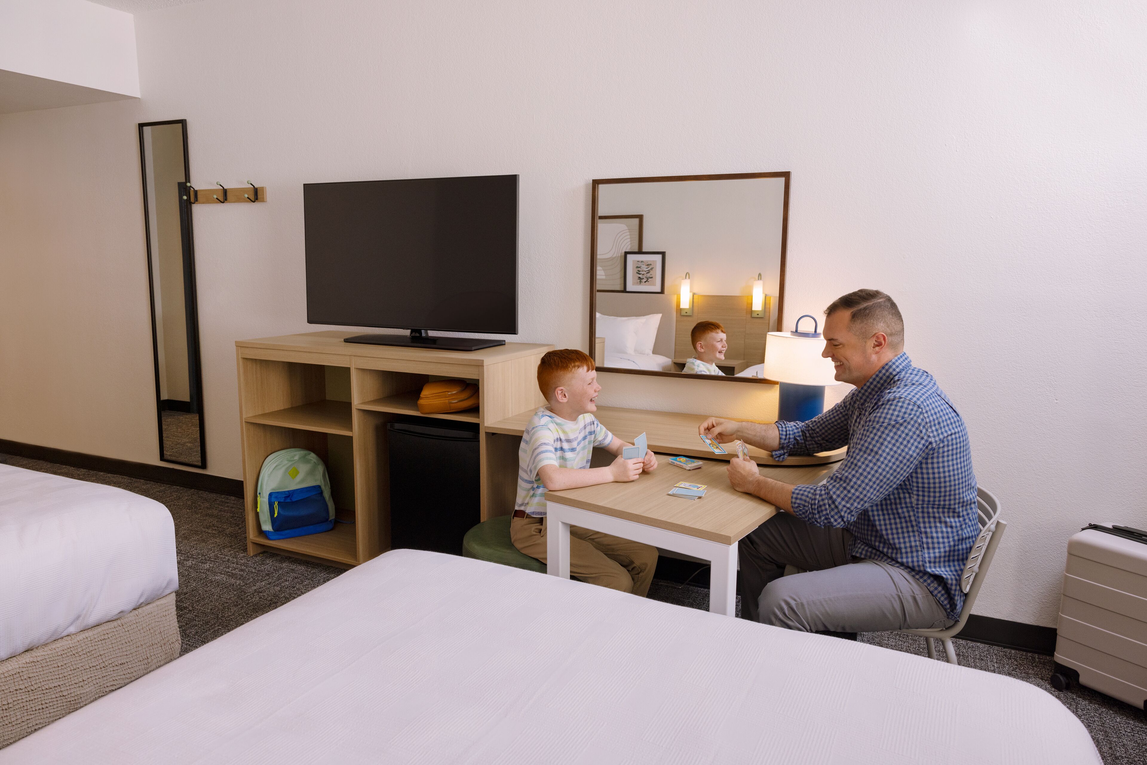 A hotel room with a bed, a desk, a television, and a mirror.