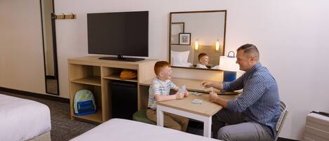 A hotel room with a bed, a desk, a television, and a mirror.