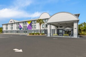 Un hotel con diseño moderno, que cuenta con un amplio estacionamiento y una fachada geométrica distintiva.