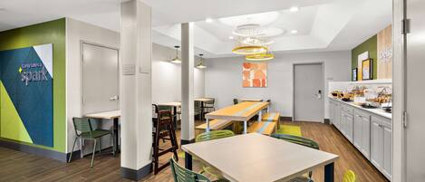 A modern dining area with a wooden table, green chairs, and a yellow pendant light.