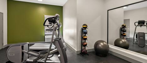 A gym with treadmills, a mirror, exercise balls, and a weight bench.