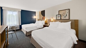 A hotel room with two beds, a desk, and a chair. There are wall-mounted lamps and artwork. - Spark by Hilton Tifton (Tifton)