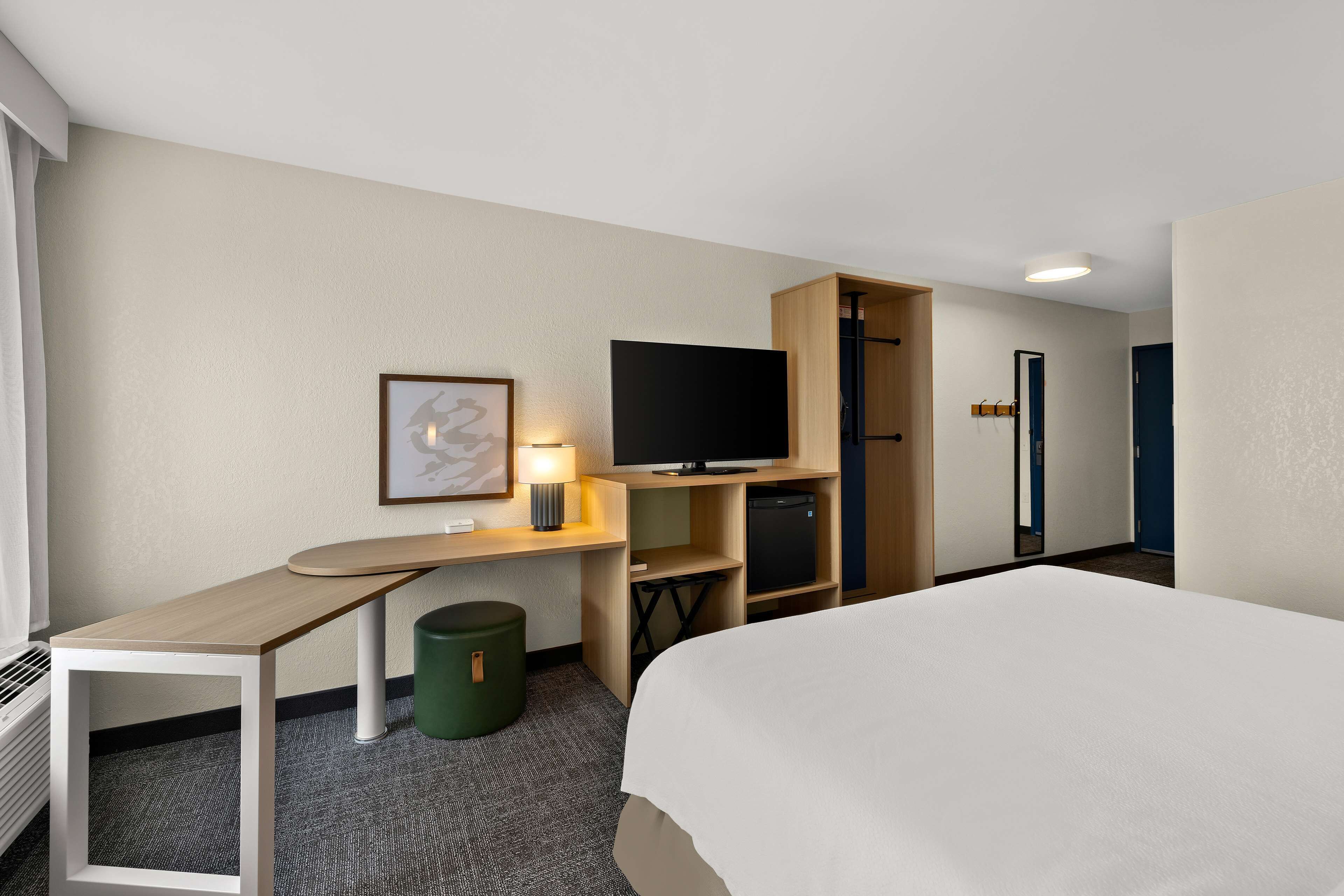 Una habitación de hotel con cama, escritorio, televisor y armario.