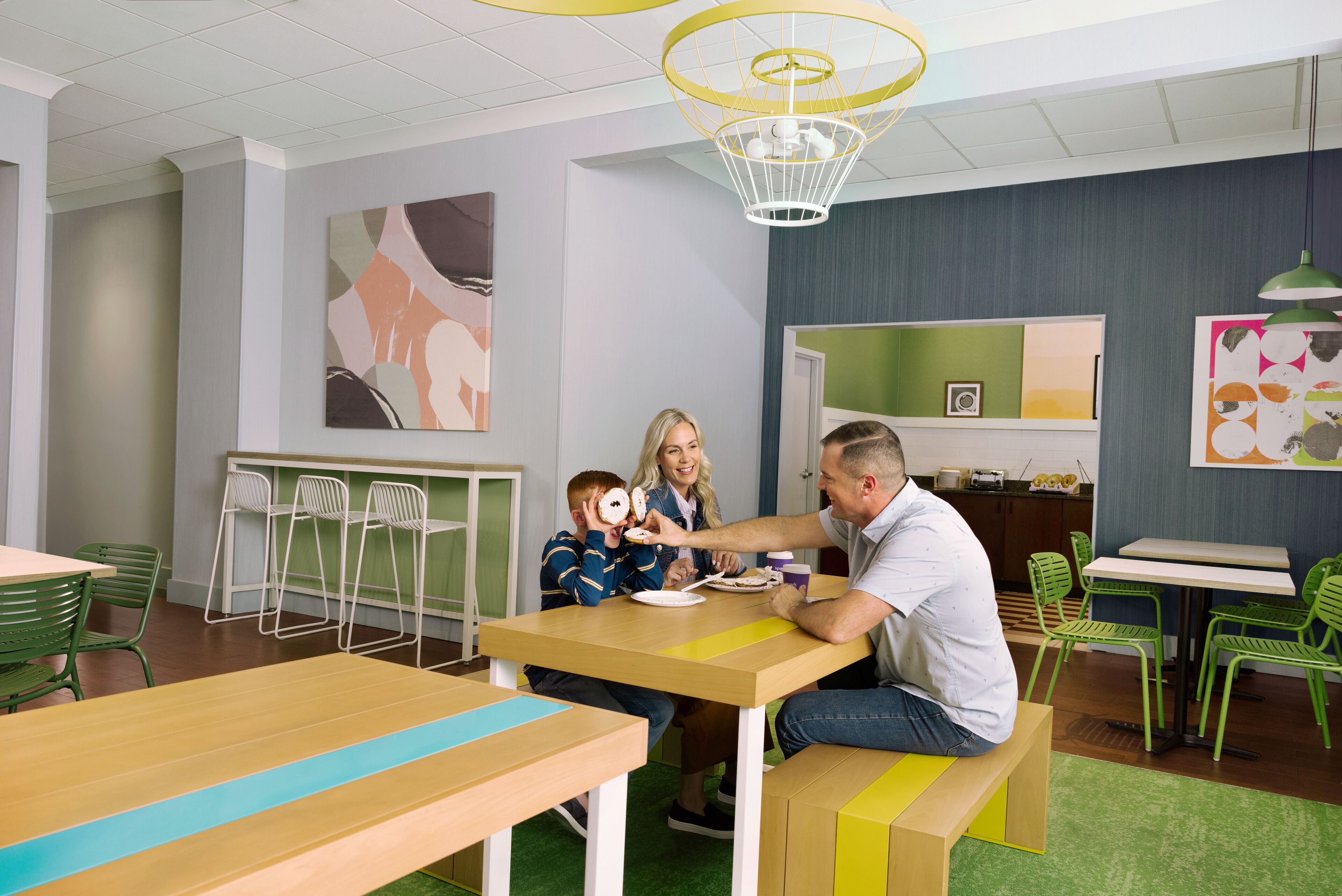 Un espace repas avec des tables et des chaises, un comptoir et des œuvres d’art accrochées aux murs.