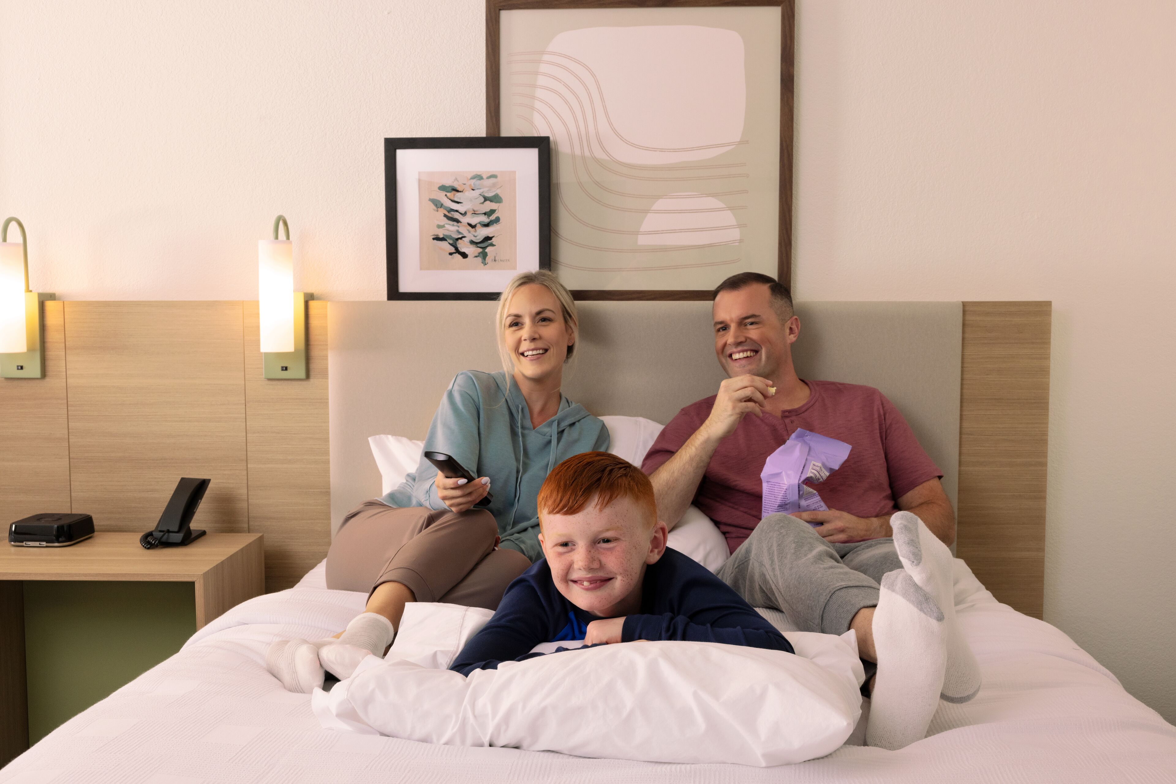 A hotel room with a bed, bedside table, and wall-mounted light fixtures.
