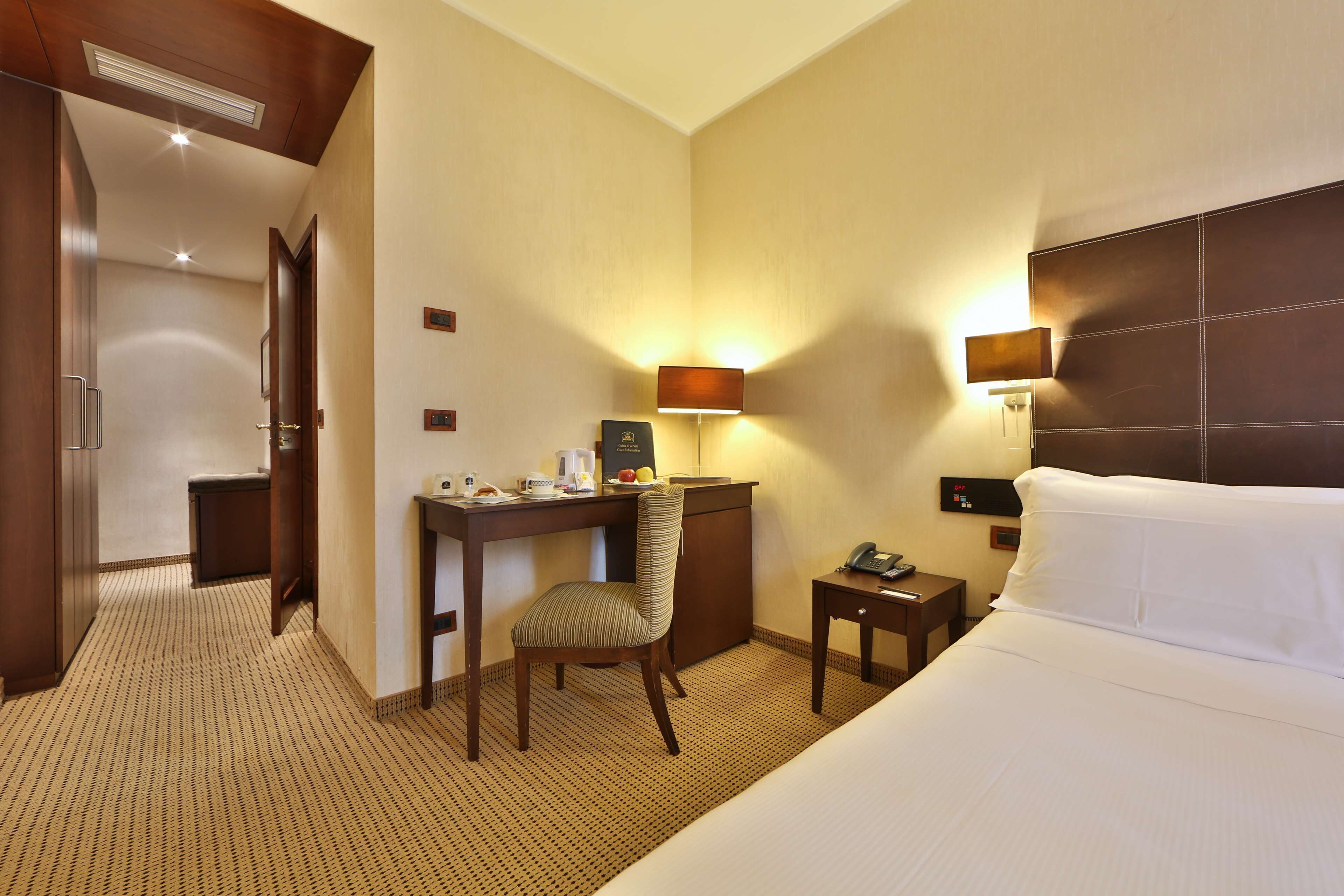 Ein Hotelzimmer mit Bett, Schreibtisch, Stuhl und zwei Nachttischlampen.