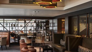 Ein modernes Interieur mit einer Sitzecke, einem Essbereich und einer Wand mit geometrischen Mustern.
