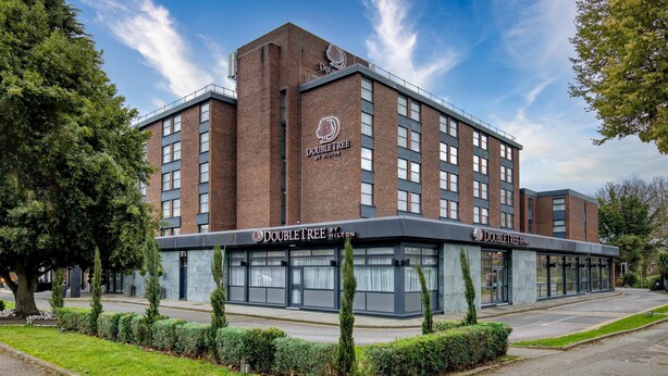 Ein DoubleTree by Hilton Hotel mit Ziegelaußenwand, großen Fenstern und einem gepflegten Rasen.