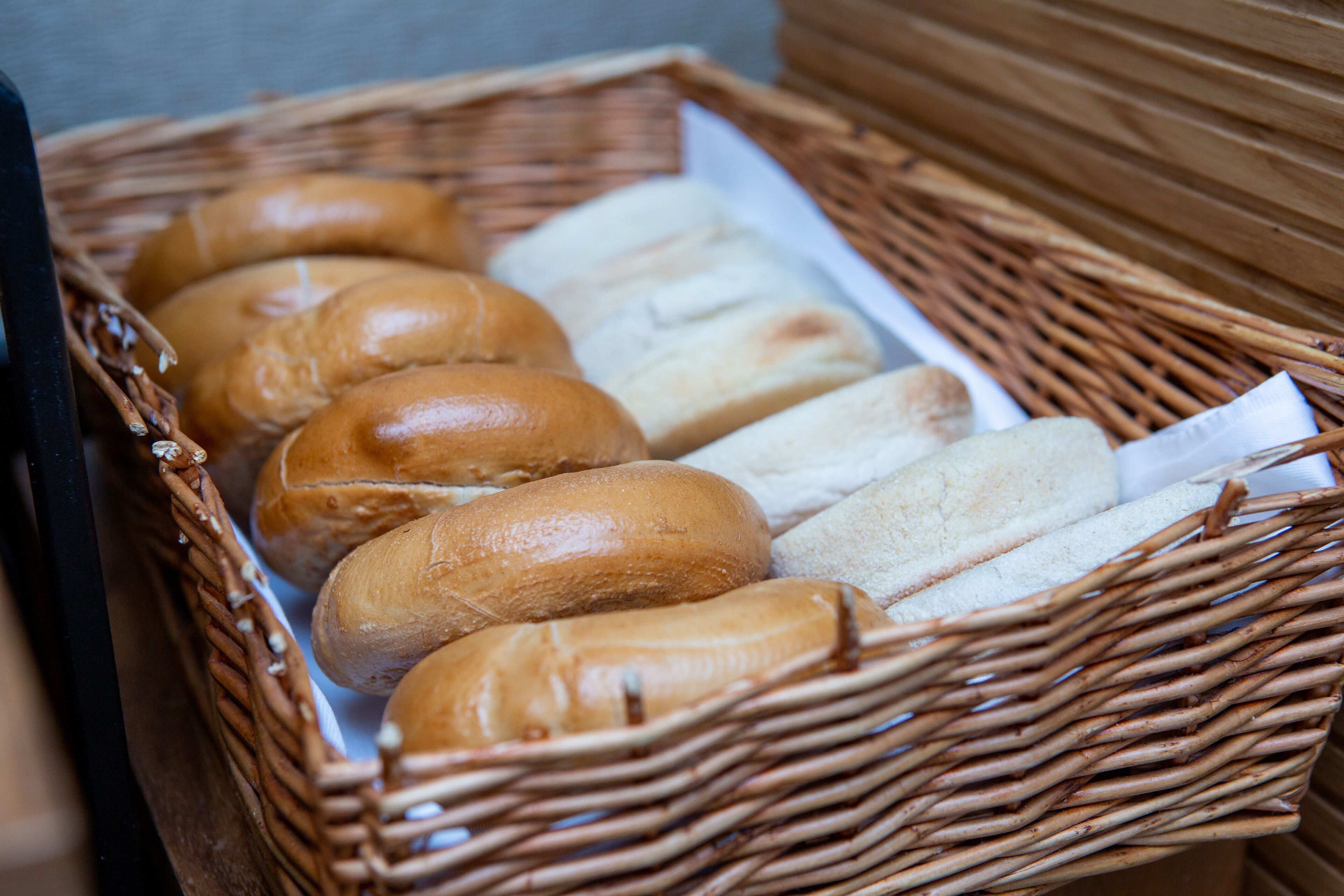A wicker basket containing various types of bread.