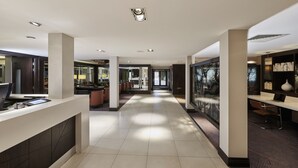 Eine moderne Hotelhalle mit einer langen Korridor, Sitzbereichen und einer Rezeption.