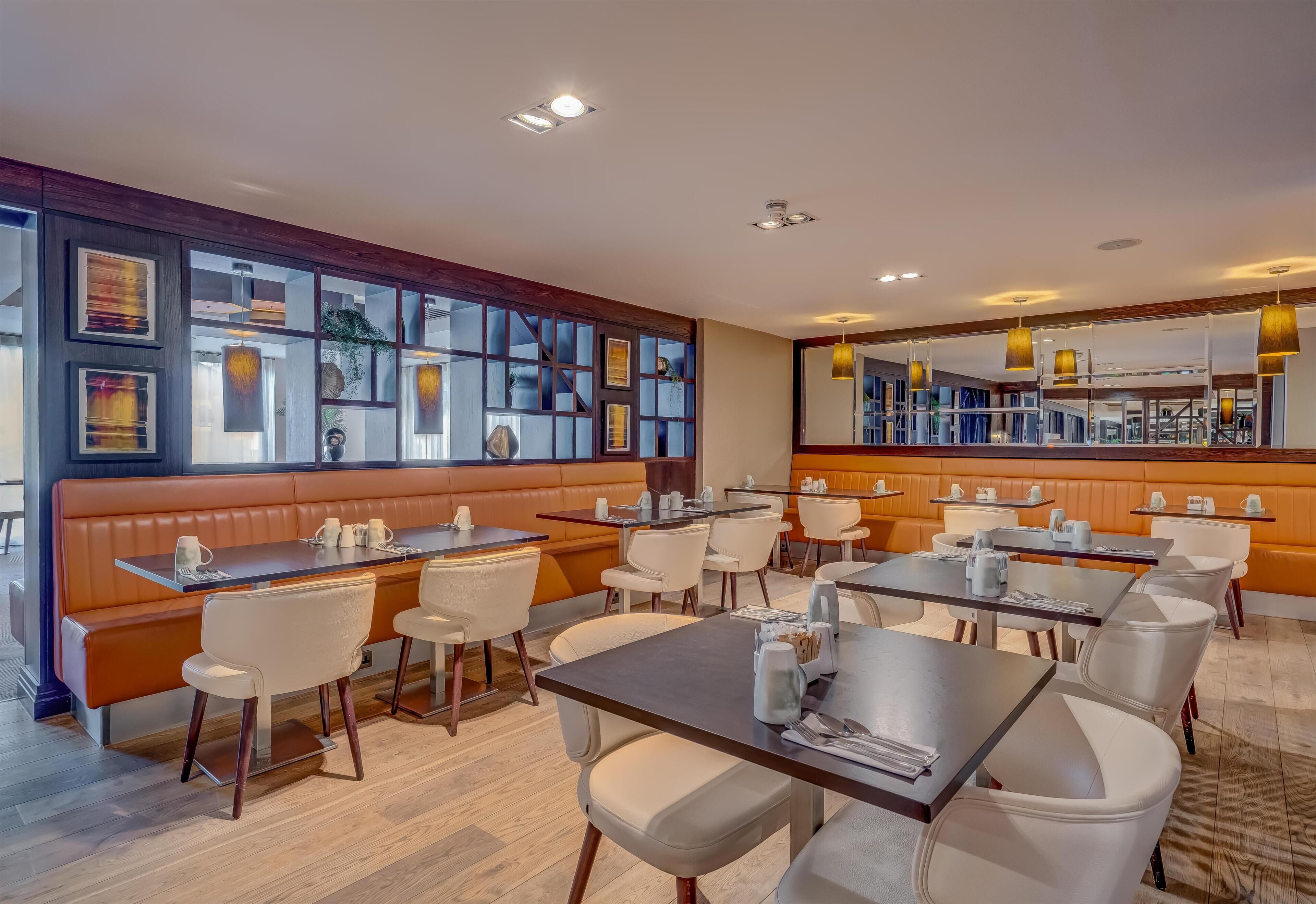 A restaurant with booths and tables, wooden paneling, and framed artwork on the walls.