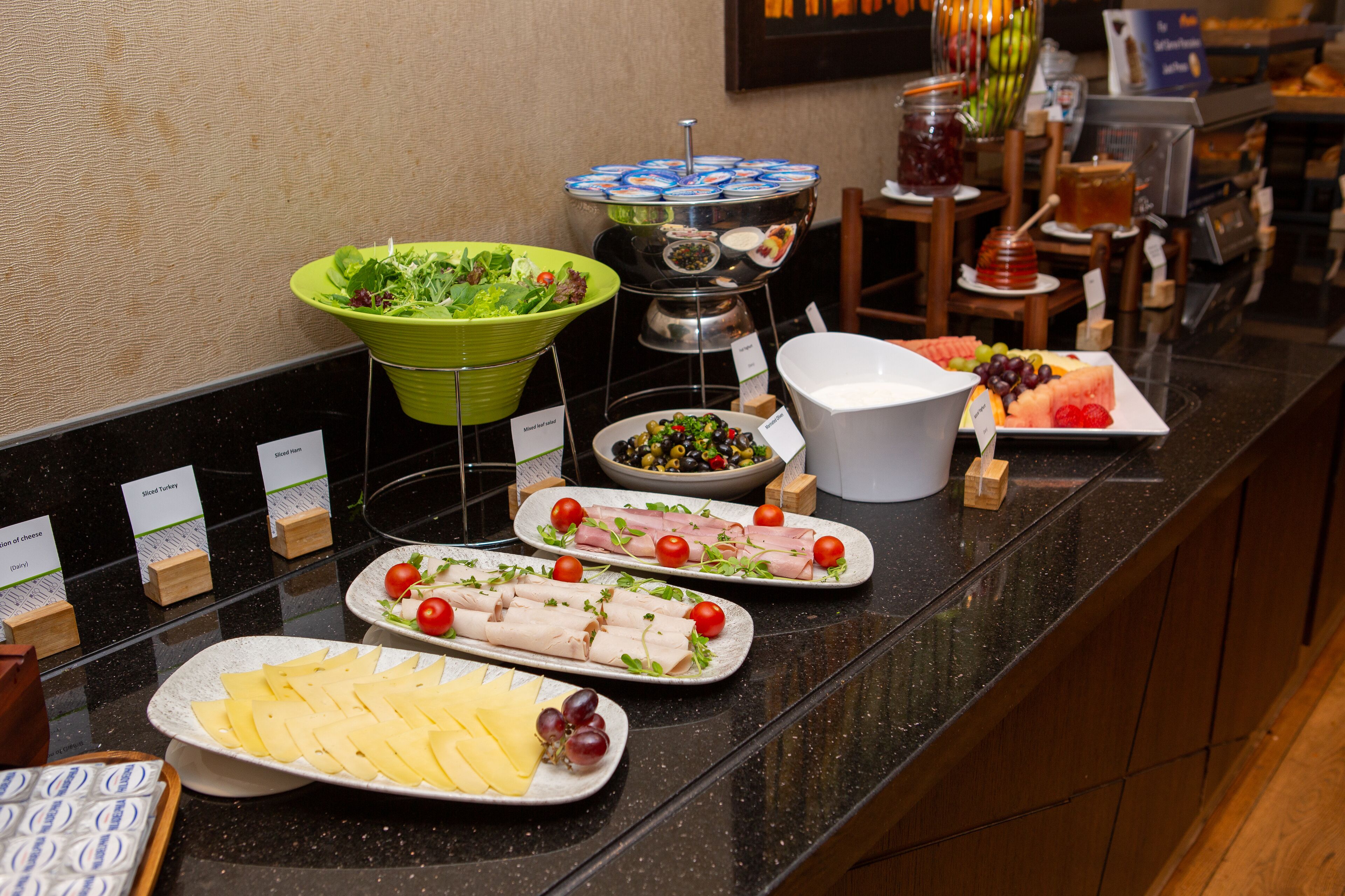 Un buffet con diverse pietanze, tra cui insalate, carni, formaggi e frutta.