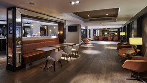 Eine moderne Hotelhalle mit Sitzgelegenheit, einer Bar und einem Fernseher.