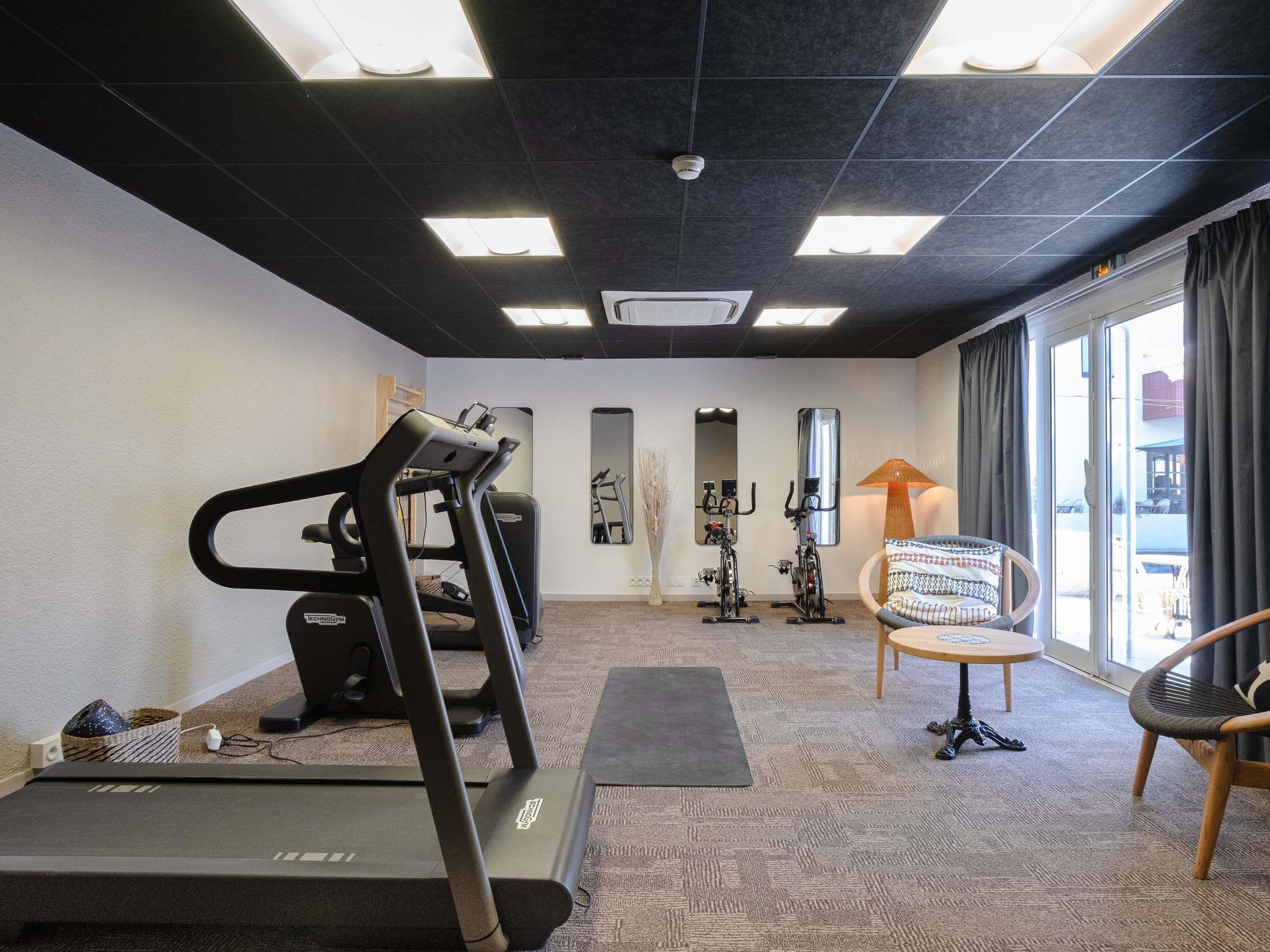 A gym with treadmills, exercise bikes, and a chair.