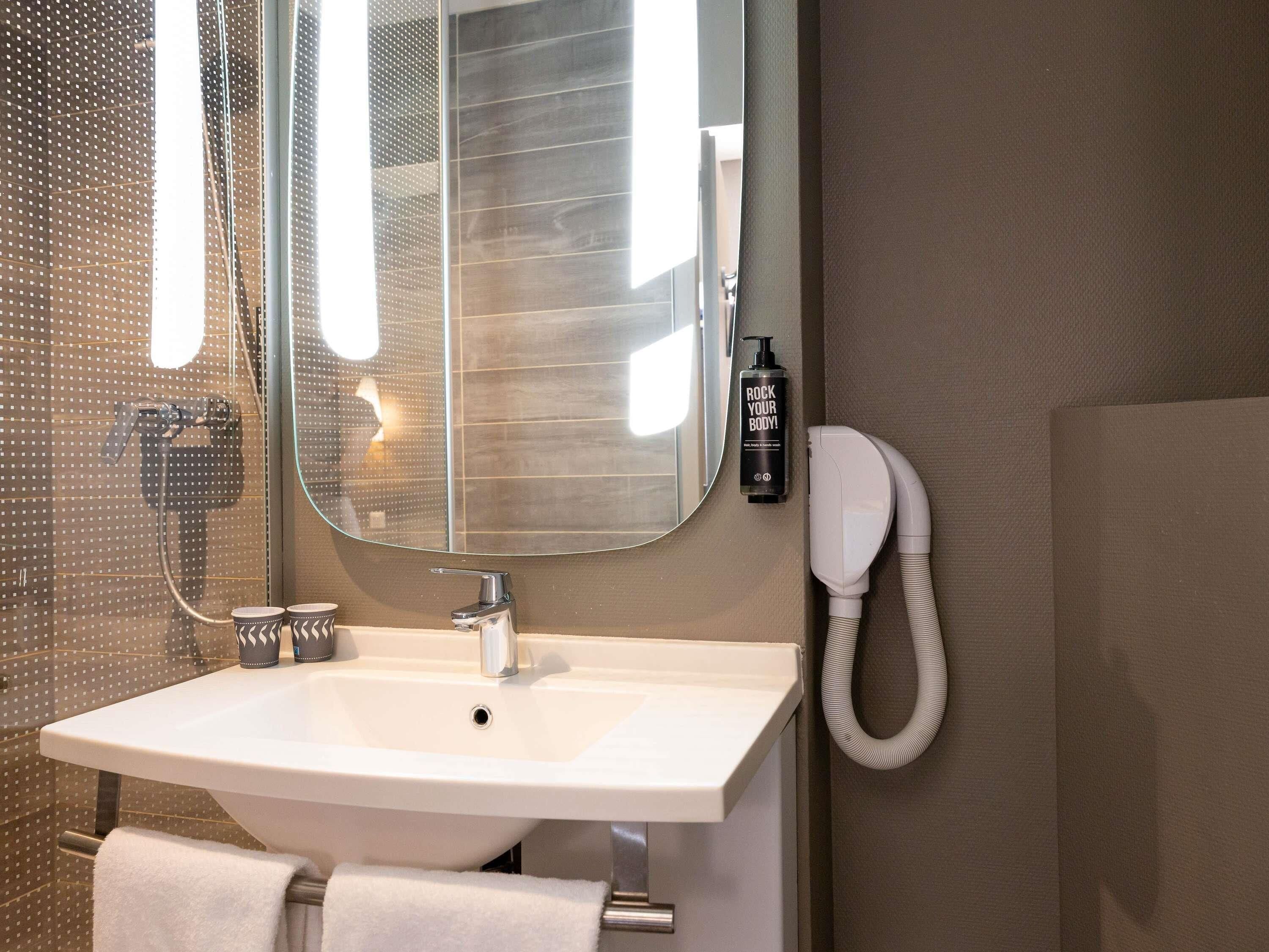 A bathroom with a sink, mirror, towel rack, and a hairdryer.