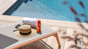 Una poltrona da piscina con un cappello da sole, occhiali da sole e flaconi di crema solare.