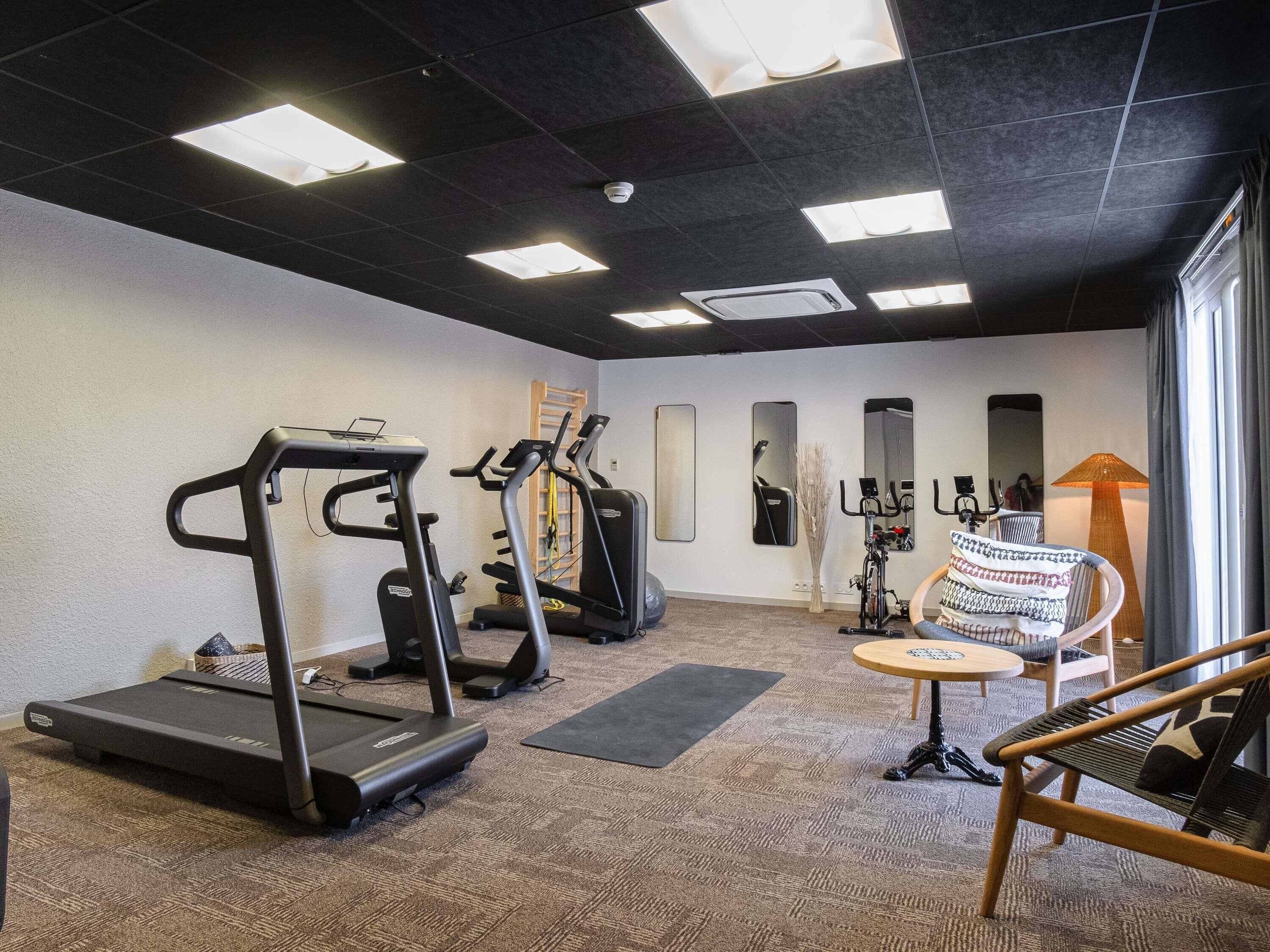 A gym with treadmills, a stationary bike, and a chair with a table.