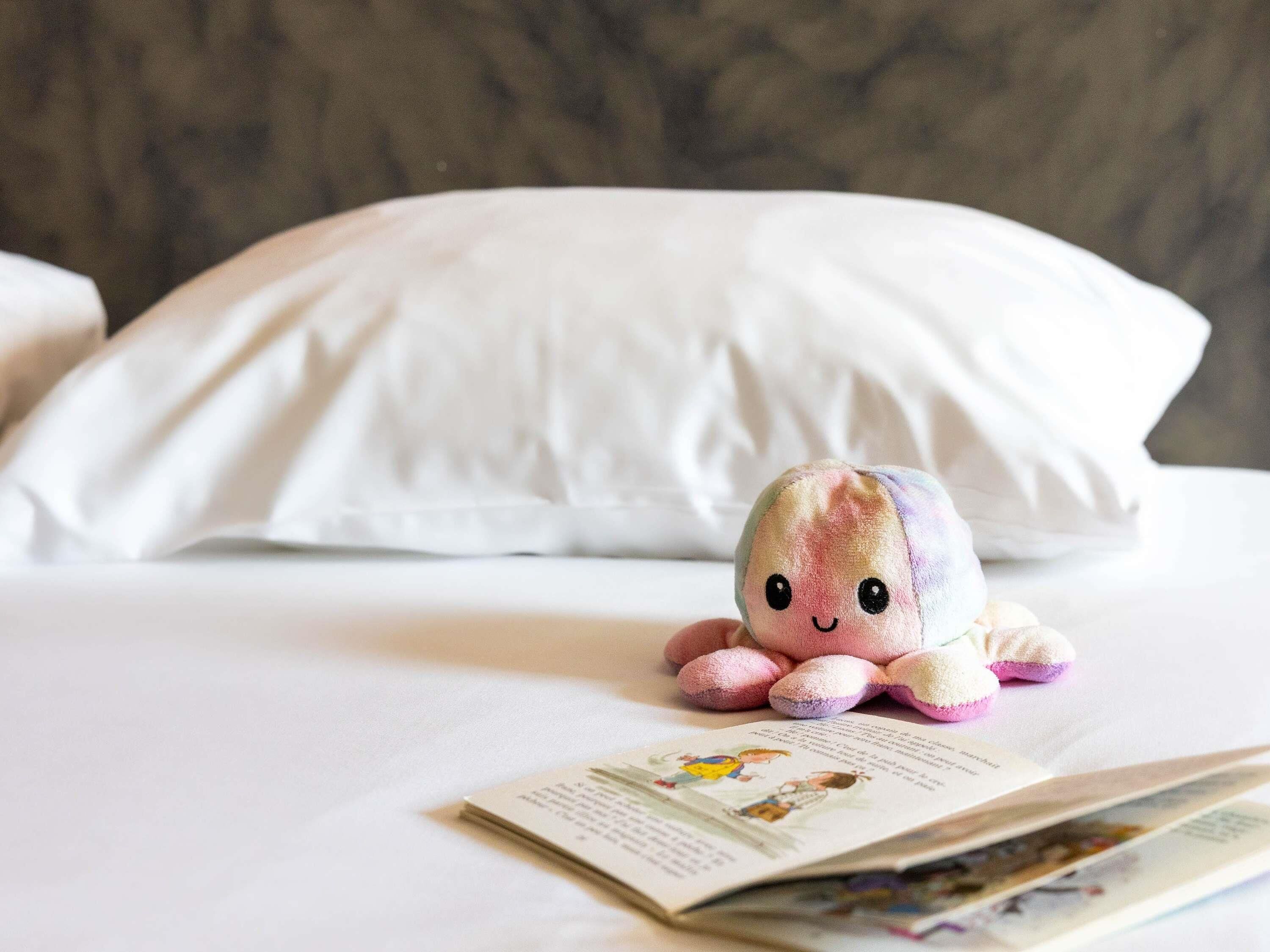 A bed with a white pillow and a plush toy on it.