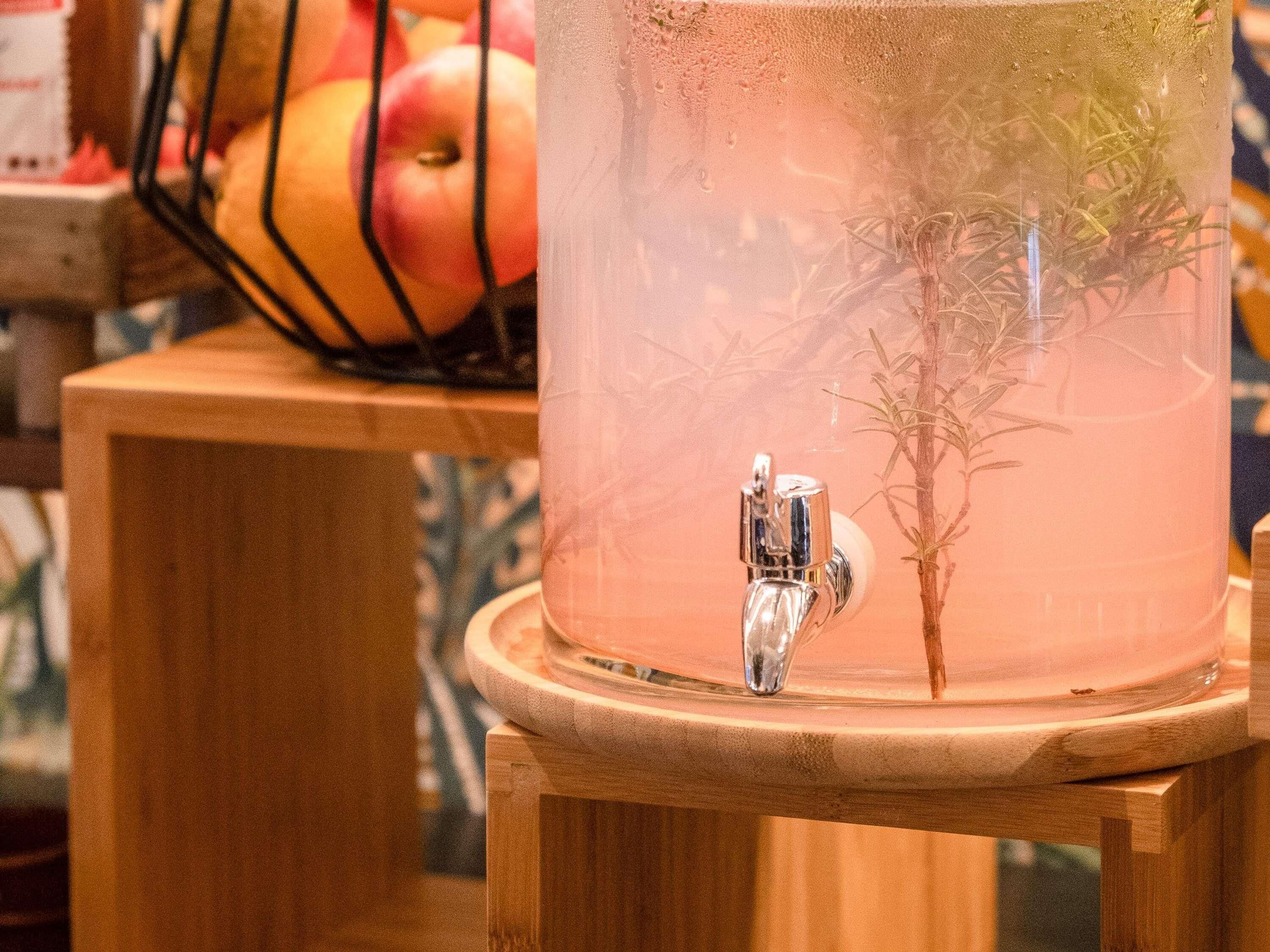 Een heldere glazen container met een kraan, geplaatst op een houten kruk.