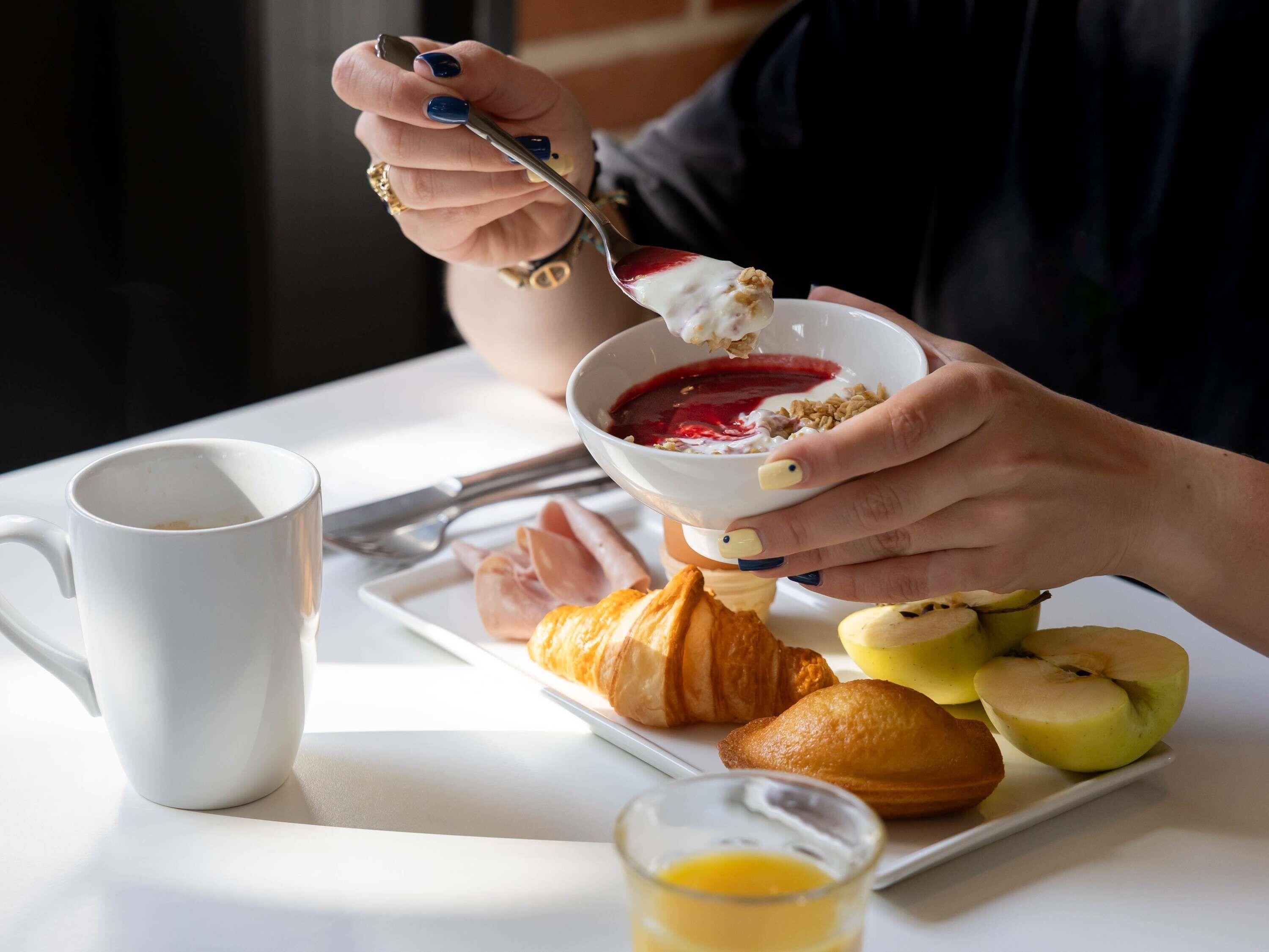 A breakfast setting with a plate of croissants, apples, and a glass of orange juice.