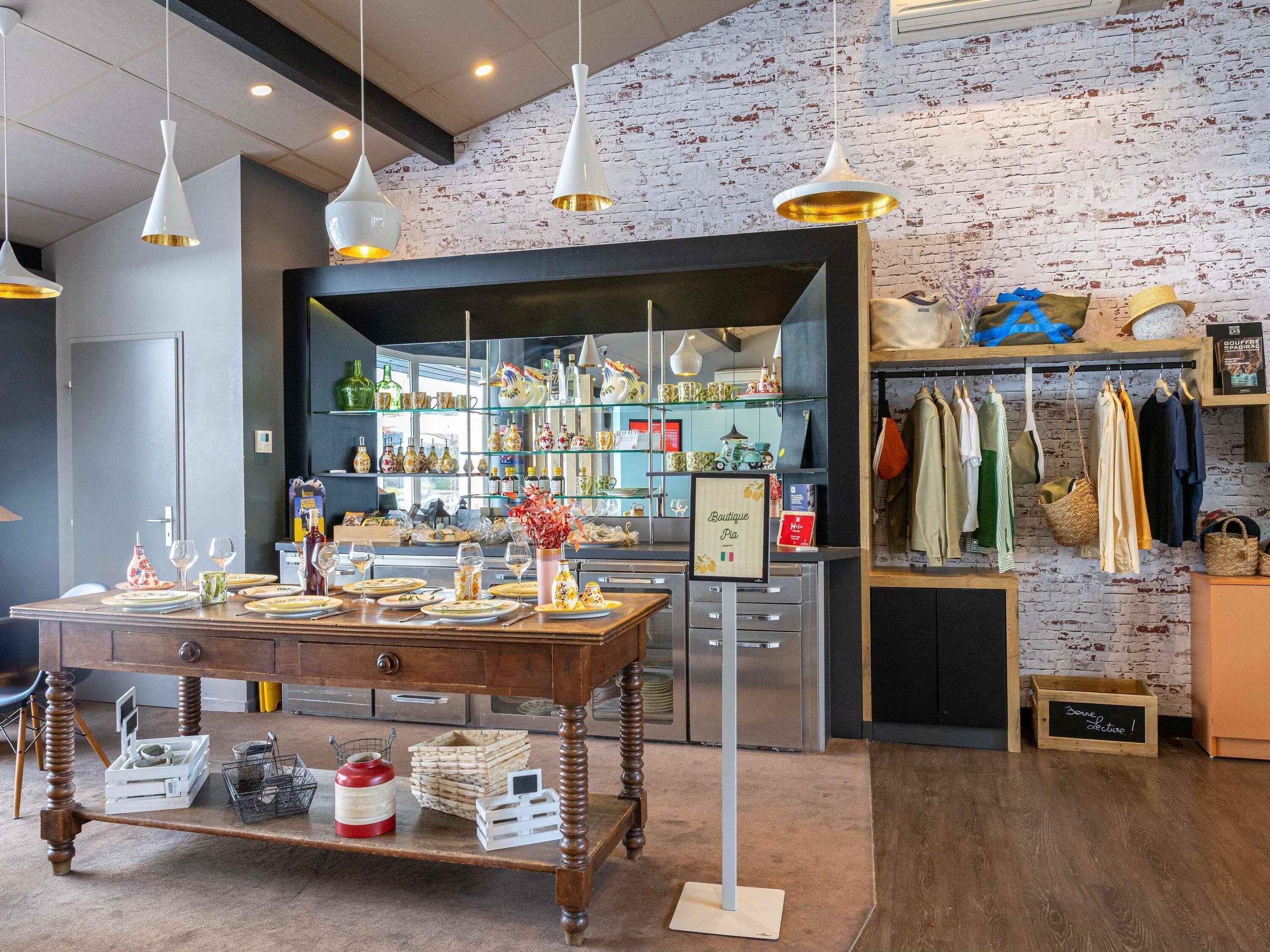 A boutique with a rustic brick wall, a dining area with a wooden table set, and a clothing rack with various garments.