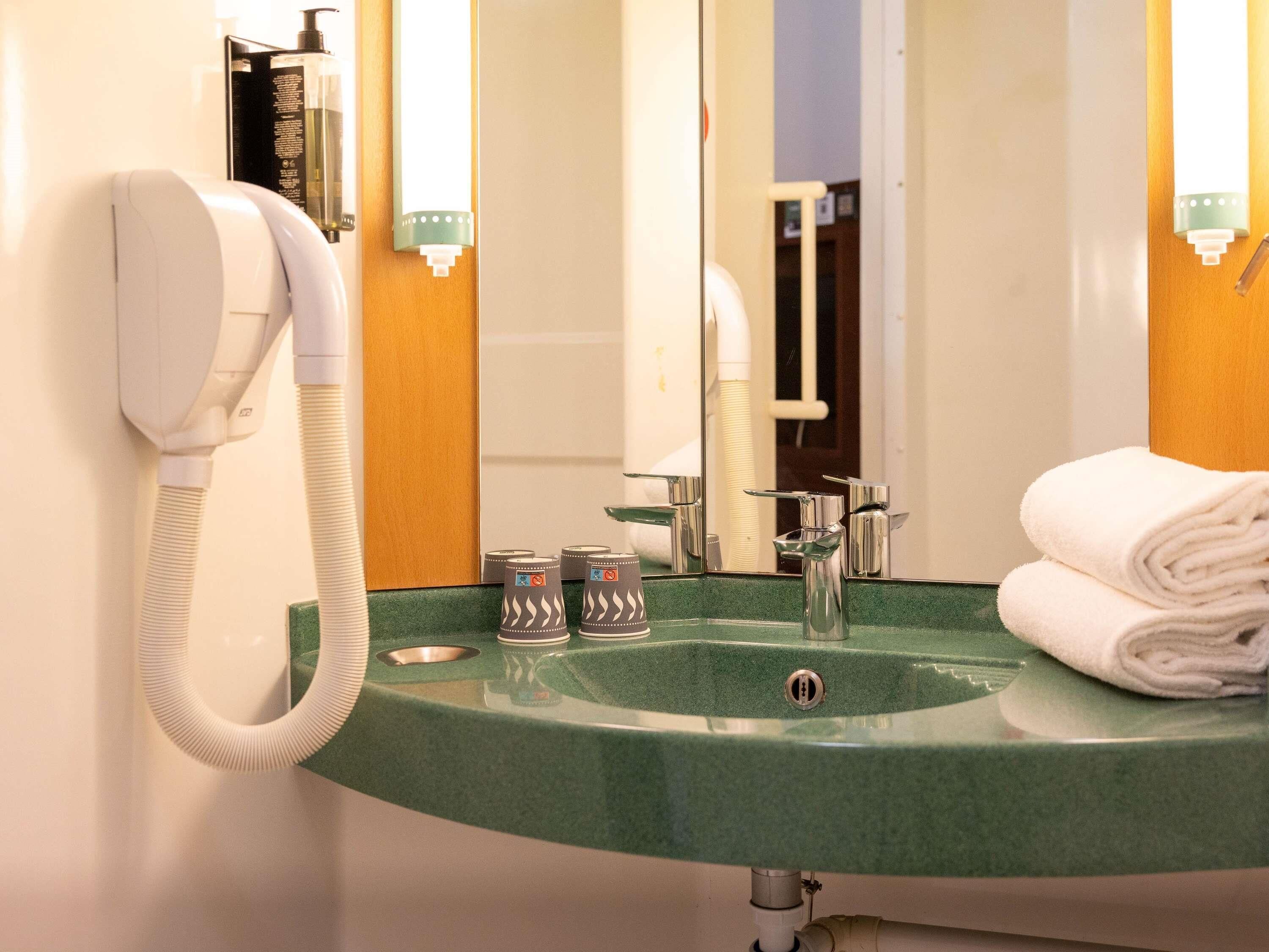 Un baño con un lavabo verde, un teléfono blanco y una toalla.