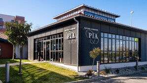 Un edificio moderno con un cartello che riporta 'TRATTORIA GOURMANDE PIA' e ampie finestre.